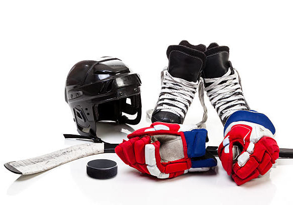 Ice hockey equipment featuring safety helmet, pair of skates, gloves, stick and a hockey puck. Isolated on white background.